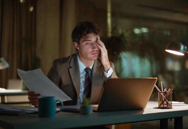 dirigeant fatigué analysant ses documents et prenant des décisions pour son entreprise